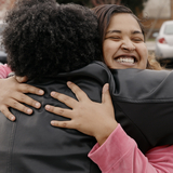 A young woman embraces her neighbor